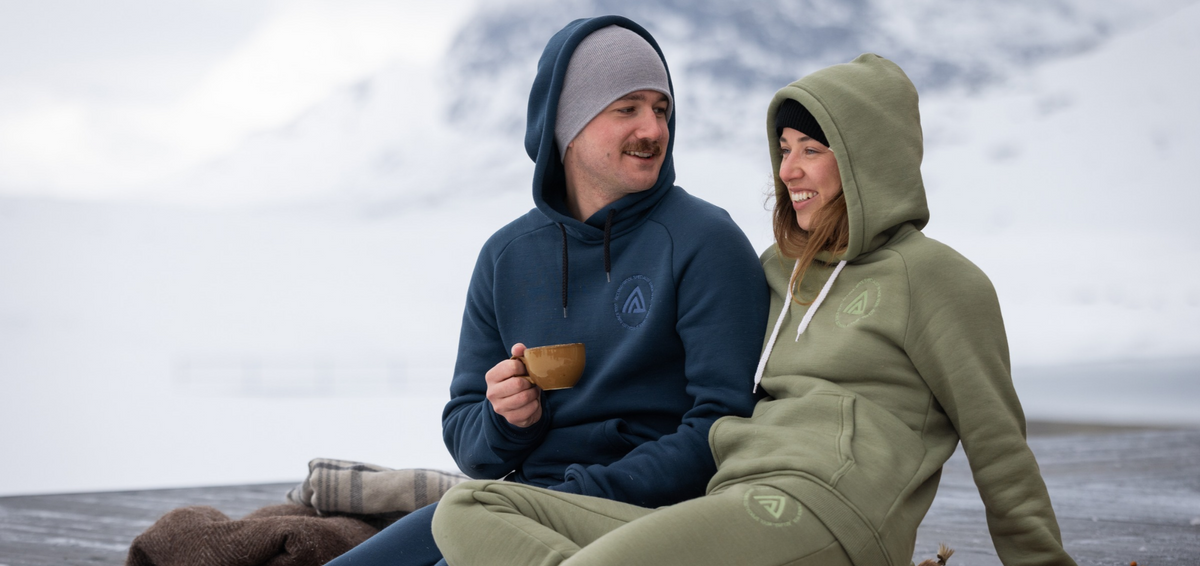 Two people wearing Aclima FleeceWool merino hoodies outdoors in winter