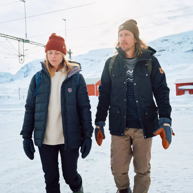 A couple wearing Fjallraven outdoor gear in the snow for the Fjallraven Buyer's Guide