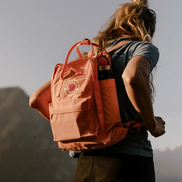 A woman in the mountains with a Fjallraven Kanken backpack