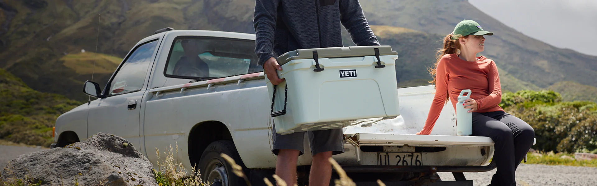 Two people with a Yeti cooler in a scenic outdoor setting.